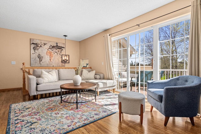 living area featuring baseboards, a chandelier, and wood finished floors