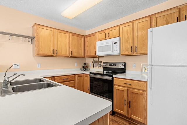 kitchen featuring white appliances, wood finished floors, a sink, and light countertops