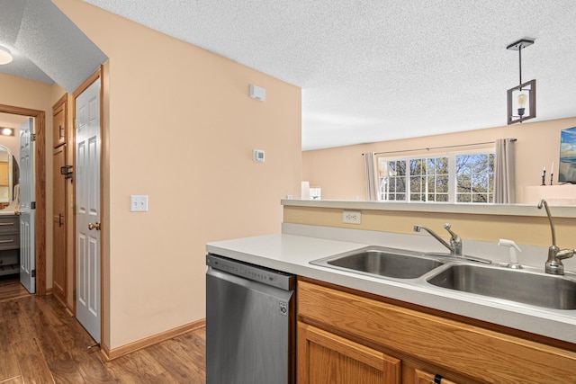kitchen featuring a sink, dishwasher, light countertops, a textured ceiling, and wood finished floors