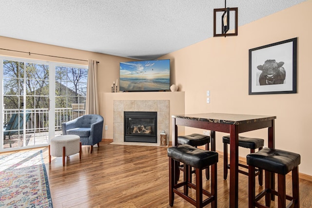 dining room with a textured ceiling, wood finished floors, and a fireplace