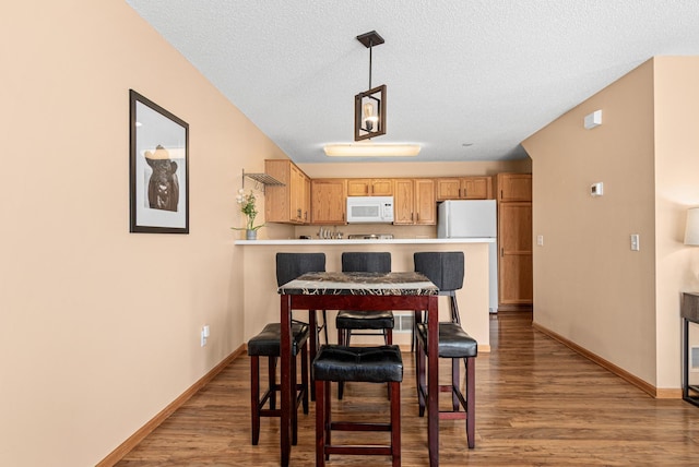 dining room featuring a textured ceiling, baseboards, and wood finished floors