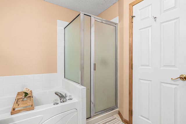 bathroom featuring a shower stall, a garden tub, and a textured ceiling