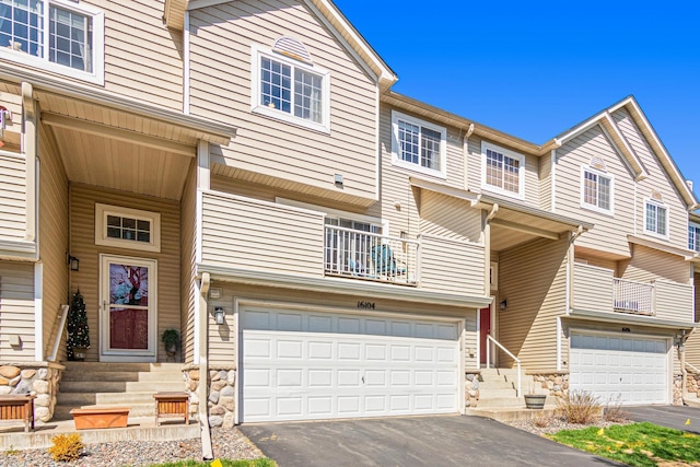 view of property with a garage, a balcony, and driveway