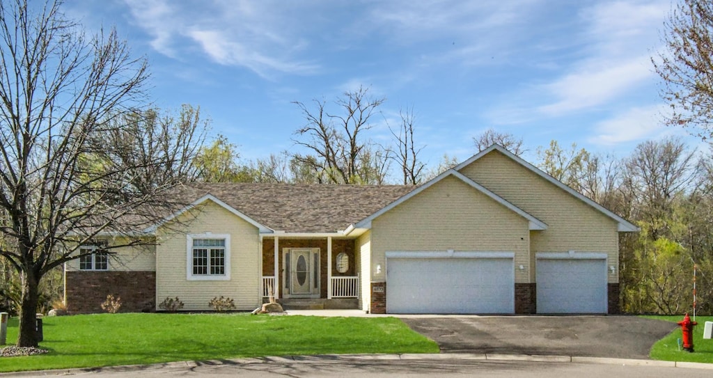ranch-style home featuring an attached garage, driveway, a front lawn, and brick siding