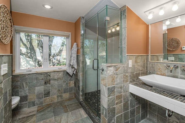 bathroom with tile walls, a shower stall, and toilet