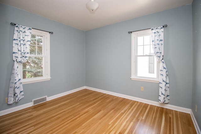 unfurnished room with baseboards, wood finished floors, and plenty of natural light