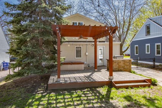 wooden terrace featuring a hot tub, a ceiling fan, fence, and a pergola