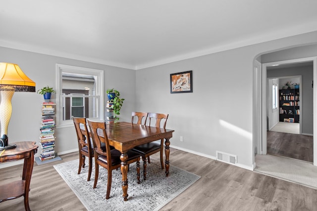 dining area with visible vents, light wood-style flooring, and baseboards