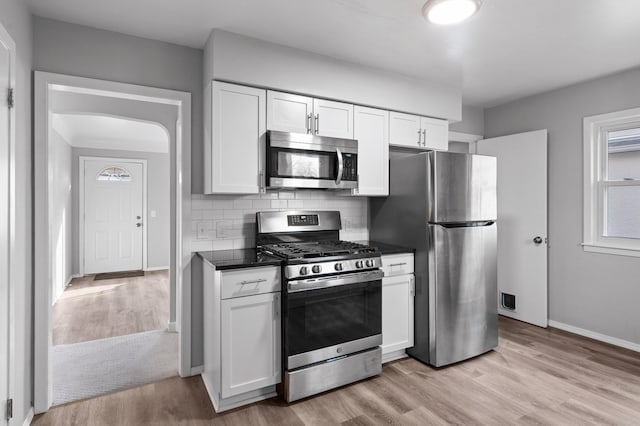kitchen featuring white cabinetry, light wood finished floors, dark countertops, and stainless steel appliances