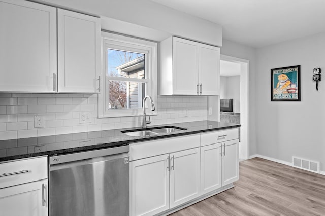 kitchen featuring stainless steel dishwasher, visible vents, white cabinets, a sink, and dark stone countertops