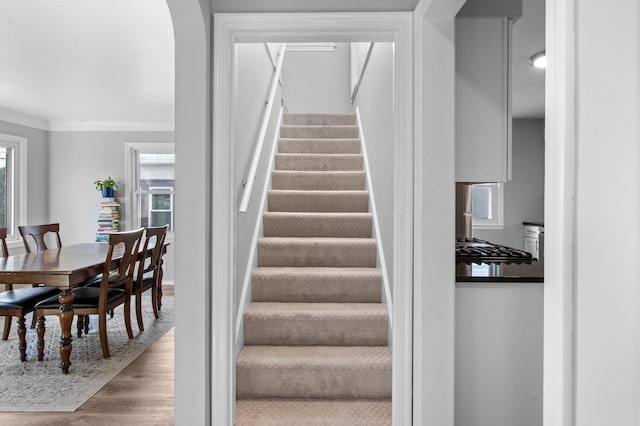 stairway featuring crown molding, arched walkways, and wood finished floors