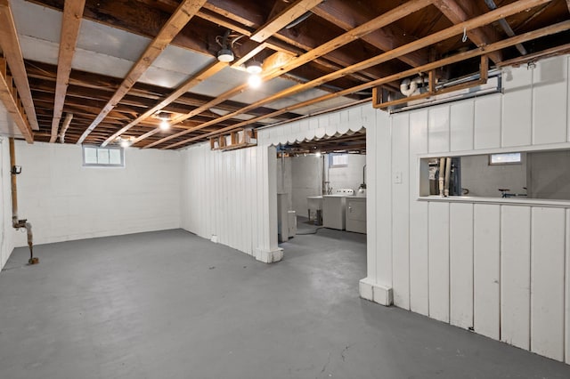 below grade area featuring washing machine and clothes dryer and concrete block wall