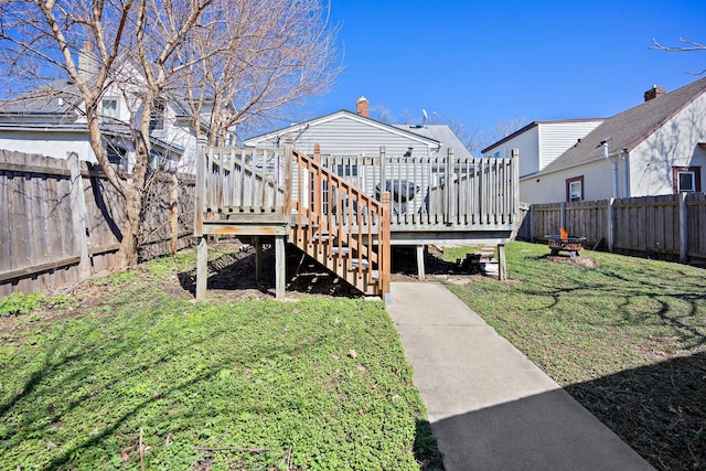 rear view of property featuring a fenced backyard, a yard, and a deck