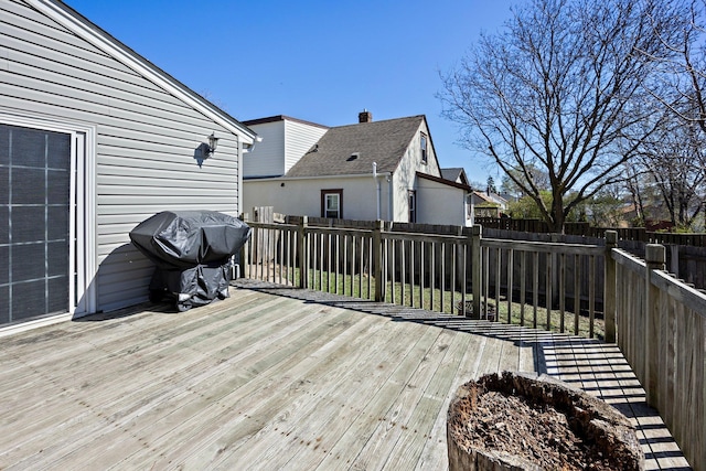 wooden deck with a fenced backyard and grilling area