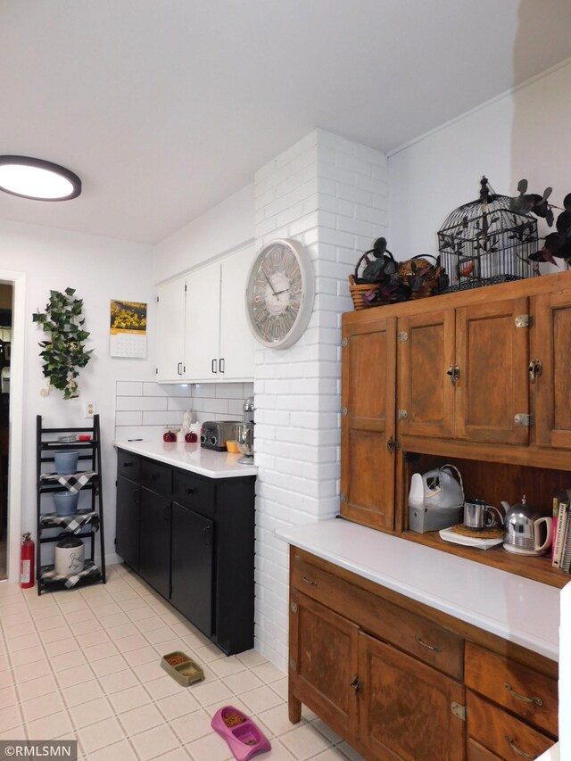 kitchen featuring light countertops, white cabinets, light tile patterned flooring, and tasteful backsplash