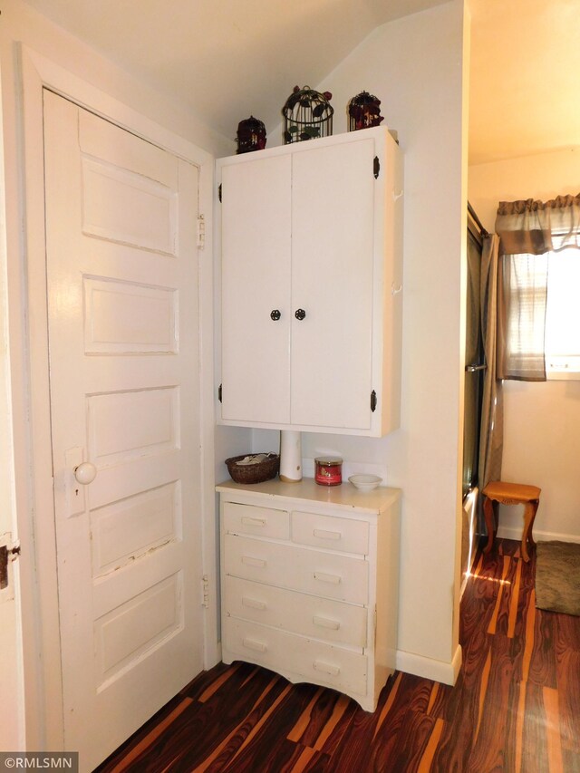 hall featuring baseboards and dark wood-style flooring