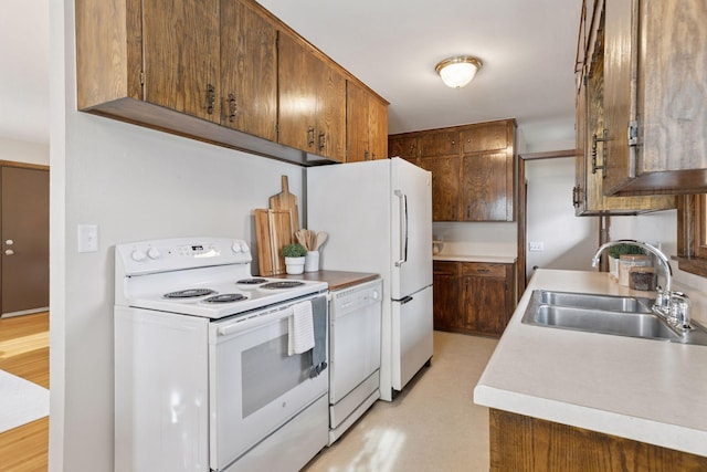 kitchen with a sink, white appliances, and light countertops
