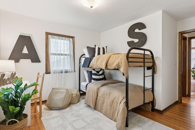 bedroom with baseboards, multiple windows, and wood finished floors