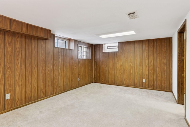 basement with carpet, plenty of natural light, visible vents, and wood walls