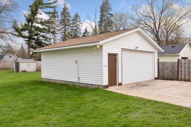 detached garage featuring concrete driveway and fence