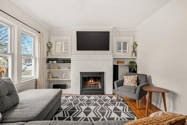 living area with ornamental molding, a brick fireplace, and wood finished floors