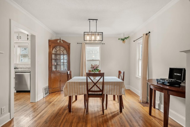 dining room with visible vents, plenty of natural light, ornamental molding, and light wood-style floors