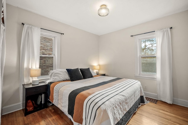 bedroom with baseboards, visible vents, and hardwood / wood-style floors