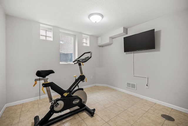 exercise area featuring baseboards, tile patterned flooring, a textured ceiling, and visible vents