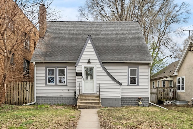 view of front facade with fence, a front yard, a chimney, a shingled roof, and entry steps