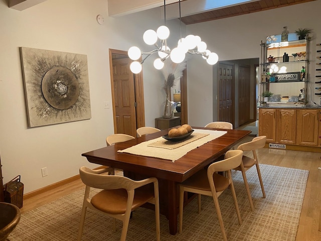 dining space with light wood-type flooring, lofted ceiling with beams, and a notable chandelier