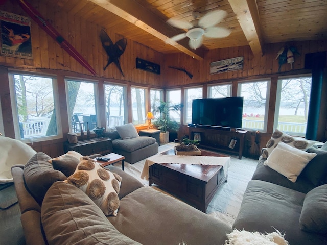 living area with wooden walls, wood ceiling, ceiling fan, and beamed ceiling