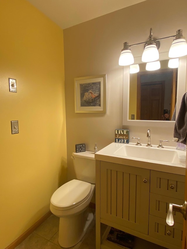 half bath with toilet, tile patterned floors, baseboards, and vanity