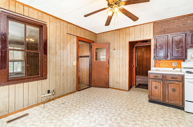 316 Main St, Belle Plaine, MN 56011 - kitchen featuring light flooring, wooden walls, white electric range, ceiling fan, and ornamental molding