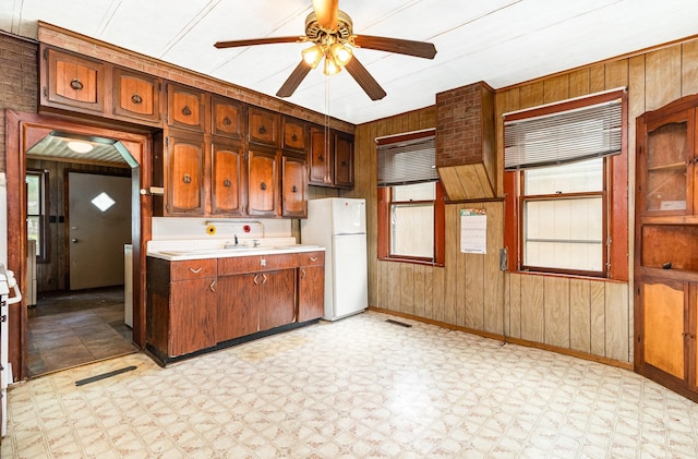 316 Main St, Belle Plaine, MN 56011 - kitchen featuring freestanding refrigerator, light flooring, wooden walls, light countertops, and a ceiling fan