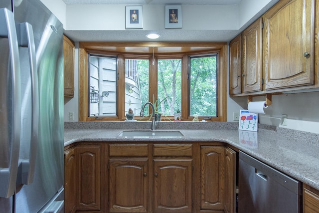 kitchen with a sink, appliances with stainless steel finishes, brown cabinets, and light countertops
