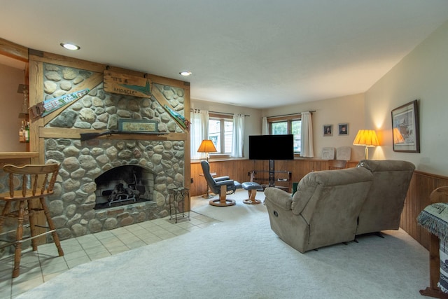 carpeted living area with a stone fireplace, recessed lighting, a wainscoted wall, and wooden walls
