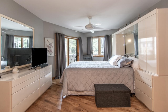 bedroom with a ceiling fan, multiple windows, light wood-style flooring, and access to exterior