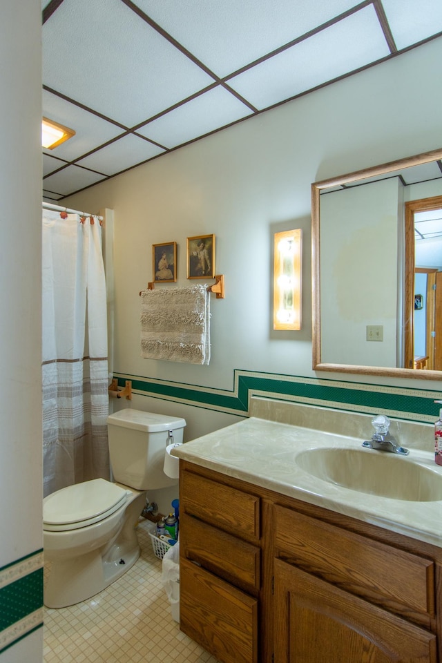 bathroom with toilet, a shower with curtain, a drop ceiling, and vanity