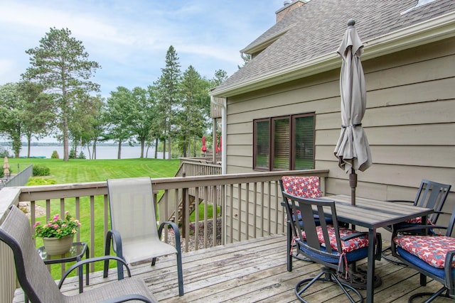 deck featuring a water view, a yard, and outdoor dining space