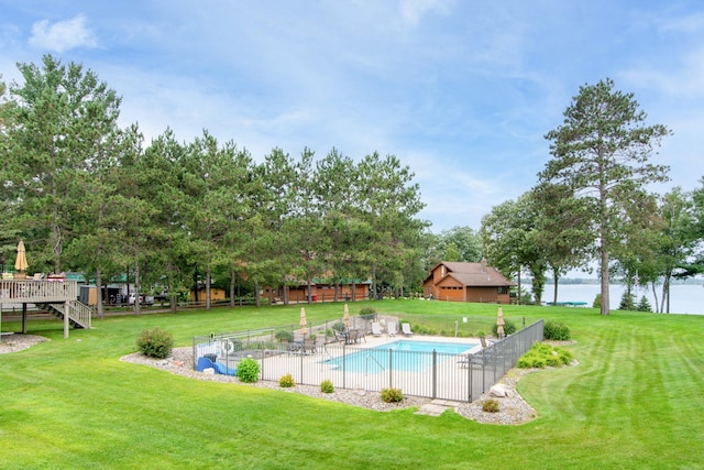 community pool featuring a water view, fence, and a yard