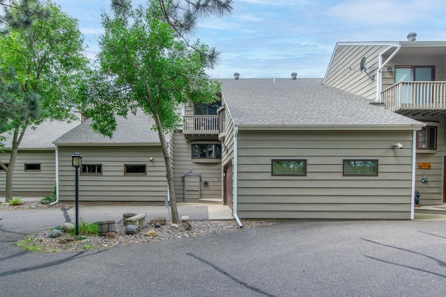 view of front of house featuring a shingled roof and a balcony