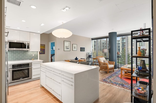 kitchen featuring visible vents, modern cabinets, light wood-type flooring, white cabinets, and appliances with stainless steel finishes