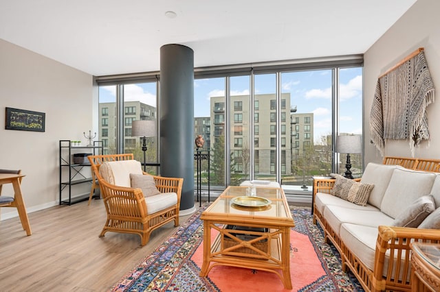 living room featuring baseboards, wood finished floors, and a wall of windows