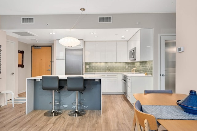 kitchen with modern cabinets, stainless steel appliances, light wood finished floors, and visible vents