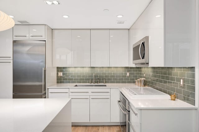 kitchen with white cabinets, appliances with stainless steel finishes, a sink, and modern cabinets
