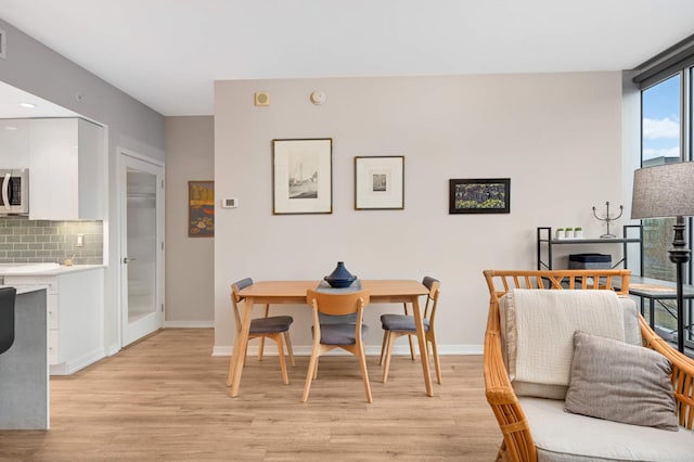 dining space with baseboards and light wood-style floors