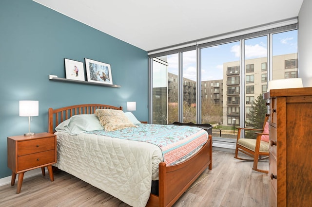 bedroom with baseboards, floor to ceiling windows, and wood finished floors