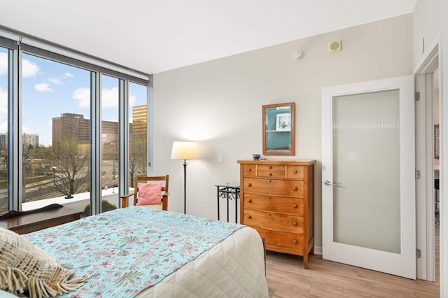 bedroom featuring expansive windows and light wood-style flooring