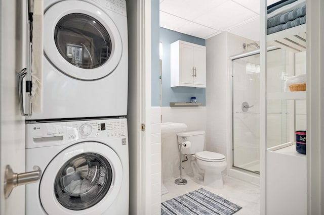 bathroom with toilet, stacked washer / dryer, and a stall shower