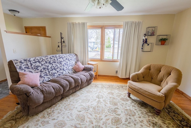 living room with ceiling fan, visible vents, baseboards, and light wood finished floors